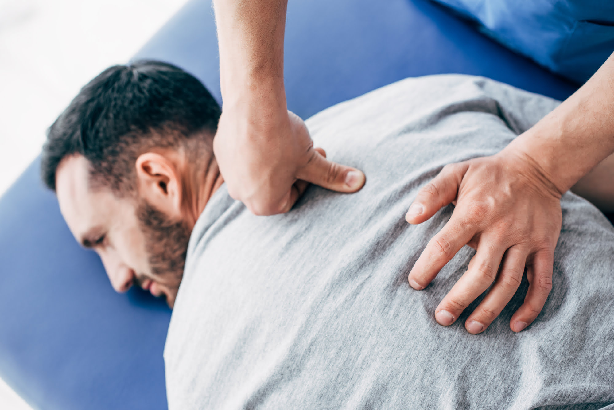 Man receiving back massage treatment on osteopath mat
